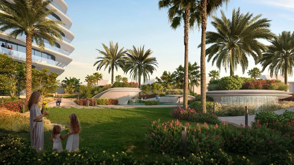 Oystra Al Marjan Island: A New Luxury Waterfront Development in Ras Al Khaimah, Ras Al Khaimah: A woman in a light dress with two young girls stands on green grass in a landscaped garden with tall palm trees, flowering shrubs, a curved concrete