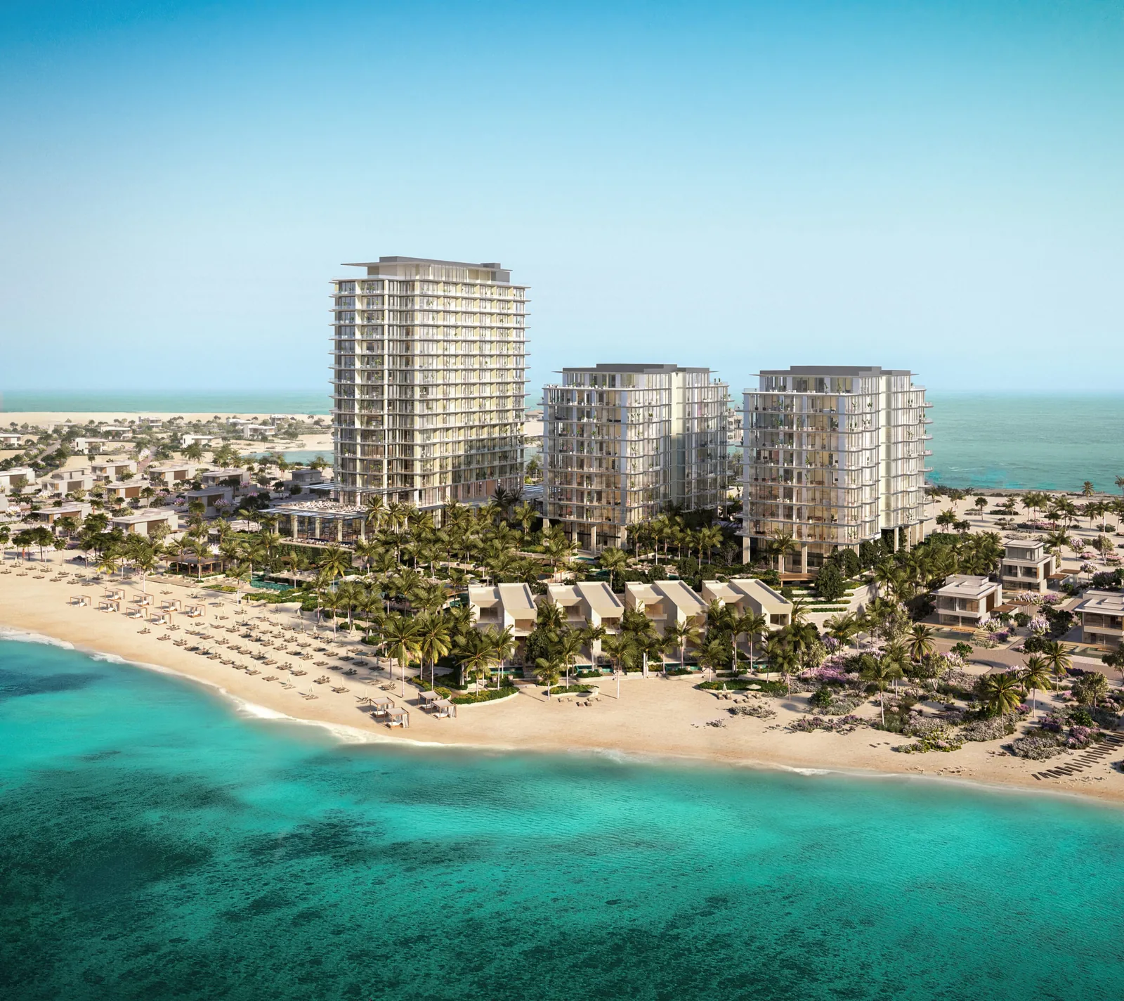 Aerial rendering of a luxury coastal resort featuring three white glass-clad residential towers surrounded by palm trees, beach cabanas and rows of sun loungers on a sandy shore fronting clear turquoise sea.